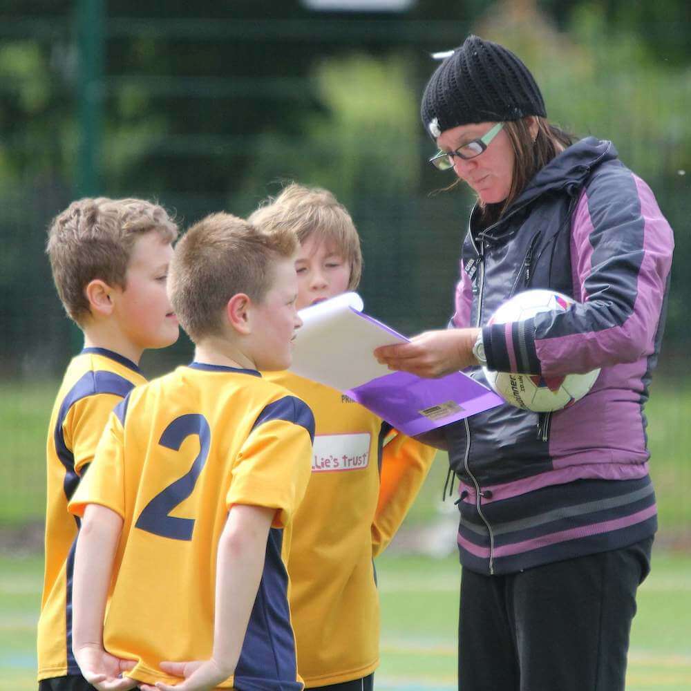Volunteer_parent_grassroots_football_coach_gives_instructions_to_young_players